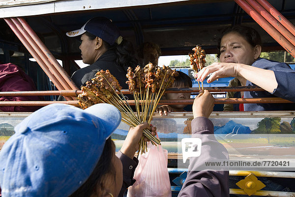 Woman Offering Food For Sale On Board Ferry Crossing The Mekong River  Near Si Phan Don In Southern Laos
