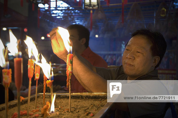 Man Lighting Up Candle In Temple