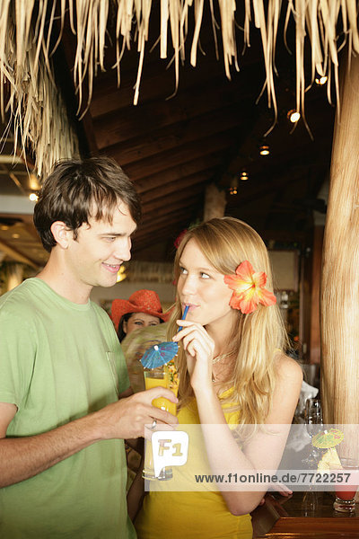 Tourist Couple At An Island Style Bar Enjoying Cocktails