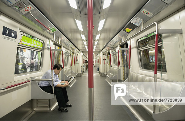 Man Sitting On An Empty Underground Subway Train Reading A Newspaper. Hong Kong  Hong Kong.