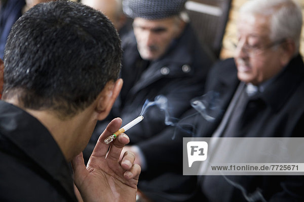 Close-Up Of Man Smoking With Senior Men In The Background At The Sha'ab Chai Khana [Teahouse]  Sulaymaniyah  Iraqi Kurdistan  Iraq