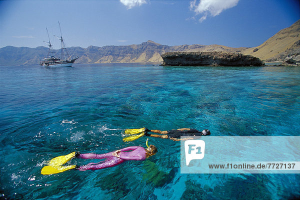 Indonesia  Couple Snorkeling Coral Reef  Boat And Coastline Background Distance D1369