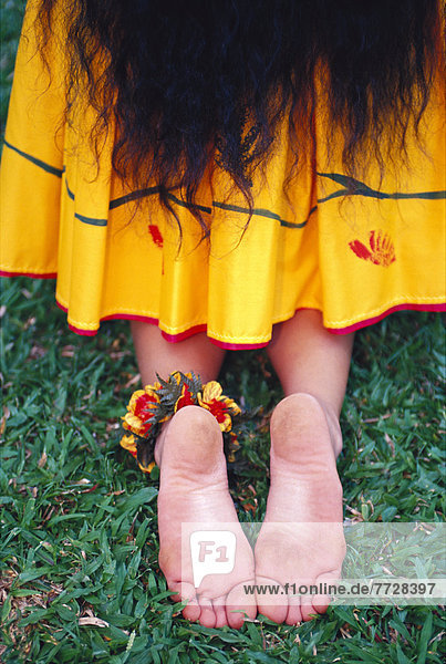 Close-Up Back View Of Woman Hula Dancer With Kupe'e On Ankle  Yellow Skirt Kneeling.