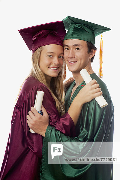 Male And Female Graduates In Cap And Gown  Holding Diplomas.