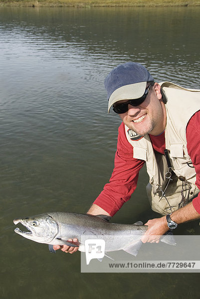 Usa  Alaska  Coghill Lake  A Fisherman Holding A Silver (Or Coho) Salmon (Oncorhynchus Kisutch).