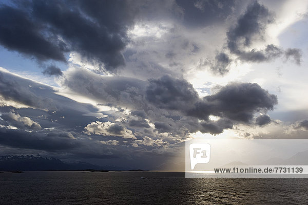 Sunlight Shining Through Dark Clouds Onto The Water And Mountains On The Coastline  Argentina