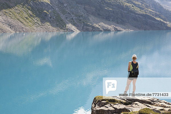 Female Hiker On Rock Cliff Overlooking Mountain Lake  Field British Columbia Canada