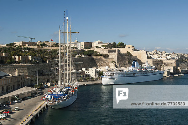 Two cruise ships moored in Grand Harbor under fortress walls  Valetta  Malta