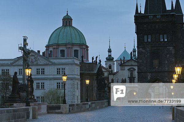 Czech Republic  Cross and statue monument with lamp posts along path illuminated at dusk  Prague