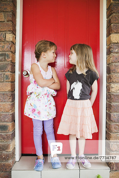 Two Girls Standing In Front Of A Red Door Making Silly Expressions At One Another  Gold Coast Queensland Australia