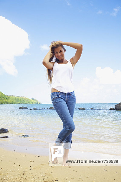 Portrait of a young woman standing on a beach at the water's edge  kauai hawaii united states of america