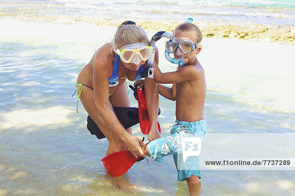 A mother and son with snorkelling gear in the shallow water Hawaii united states of america