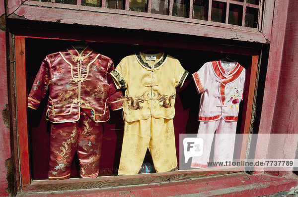 Three children's outfits in a display case in an open window Forbidden city beijing china