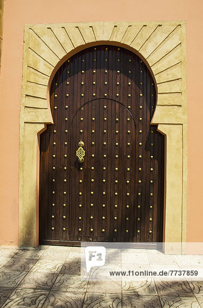 A wooden horseshoe shaped door with decorative gold rivets Marrakech morocco
