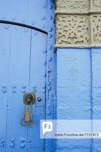 A painted blue door and wall with a unique door handle and heart shaped keyhole in old town Rabat morocco