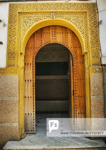 A bright yellow painted frame above an open arched doorway in old medina Casablanca morocco