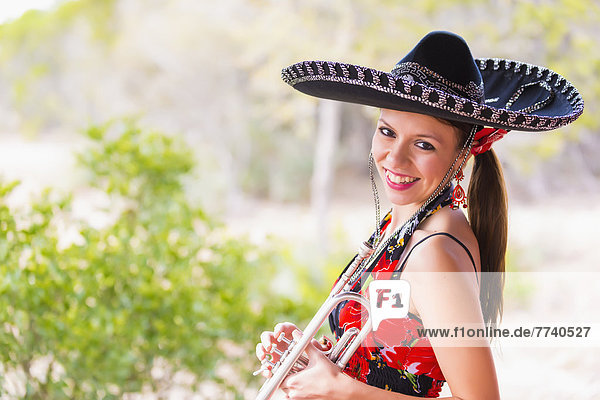 USA  Texas  Young woman holding trumpet  smiling  portrait
