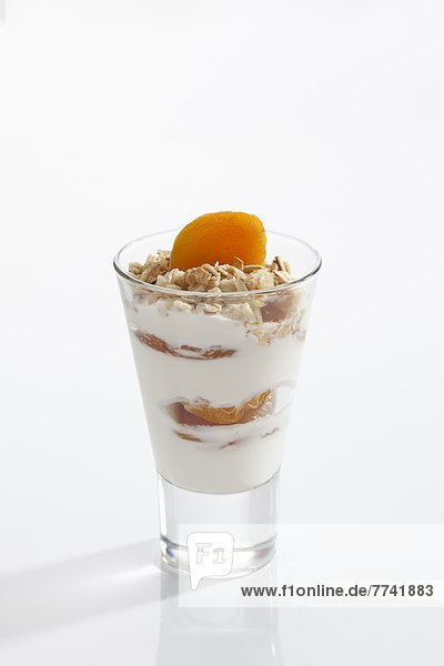 Glas Joghurt mit Müsli  Obst und Cornflakes auf weißem Hintergrund  Nahaufnahme