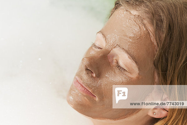Mittlere erwachsene Frau mit Schlammmaske in der Badewanne  Nahaufnahme