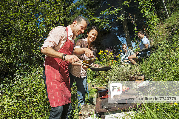 Österreich  Salzburger Land  Mann kocht für seine Familie im Garten