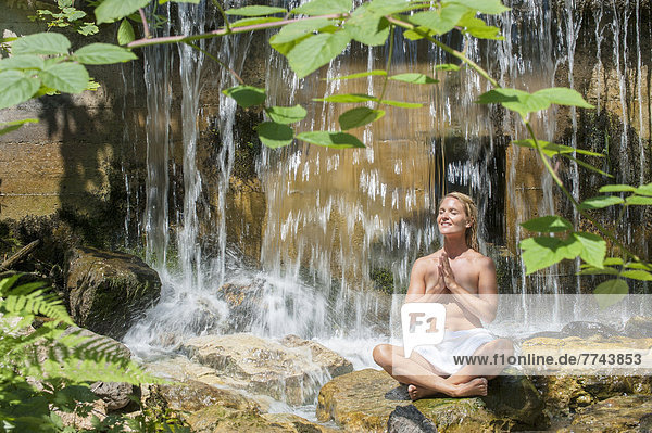 Österreich  Altenmarkt-Zauchensee  Mittelerwachsene Frau beim Meditieren am Wasserfall