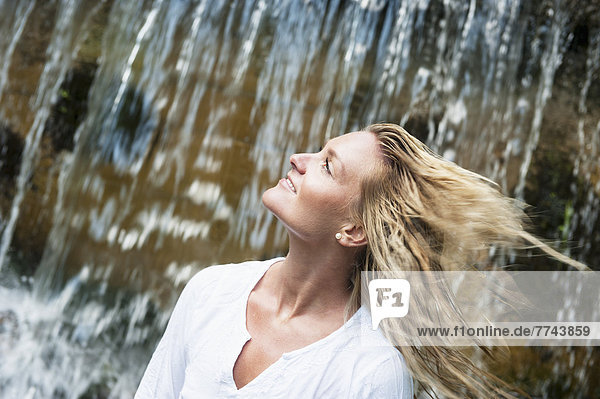 Österreich  Altenmarkt-Zauchensee  Mittlere erwachsene Frau beim Wasserfall entspannend  lächelnd