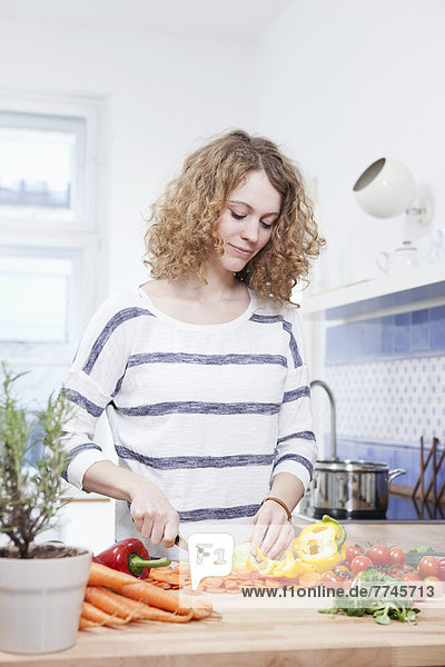 Junge Frau beim Gemüsehacken in der Küche