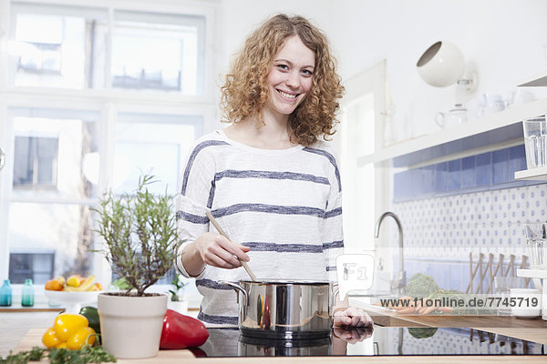 Junge Frau beim Kochen in der Küche  lächelnd  Portrait