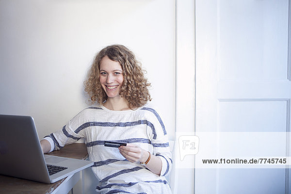 Young woman shopping online from home with laptop and credit card