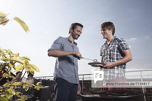 Men barbecueing on grill  smiling