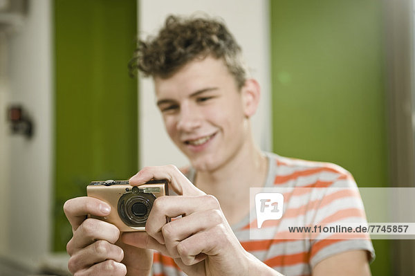 Young man using camera in cafe  smiling