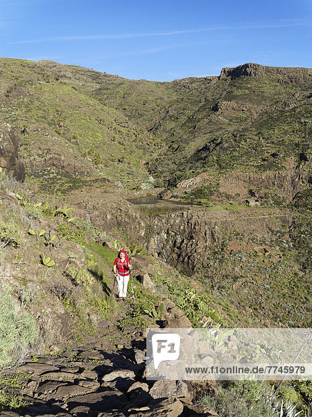 Spain  La Gomera  Mature woman hiking through Barranco de Charco Hondo