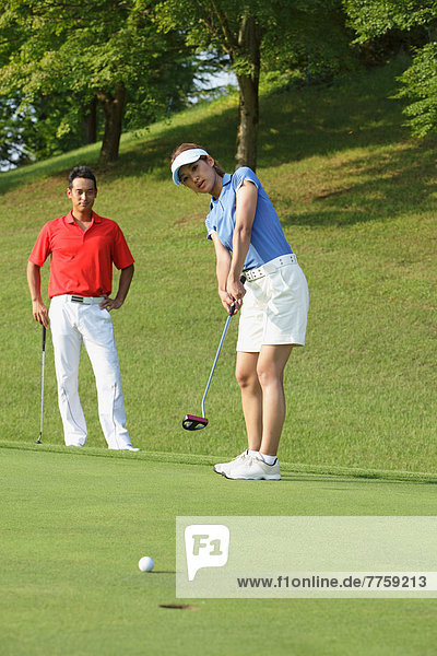 Young Woman Putting Golf Ball