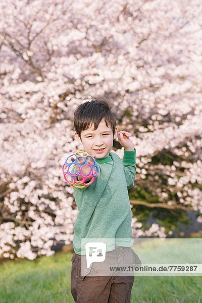 Boy playing with ball with cherry trees in the background