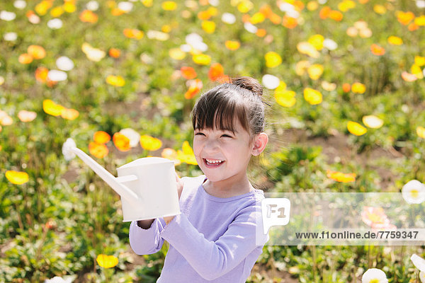 Young girl with watering can smiling
