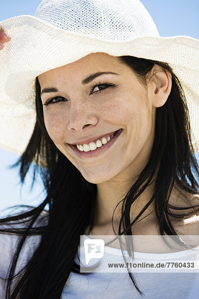 Porträt einer jungen lächelnden Frau  weißer Hut