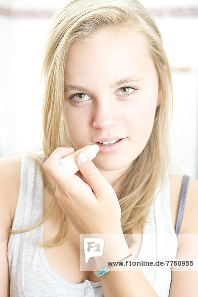 Teenage girl applying cream on her lips