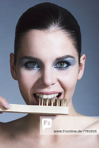 Porträt einer jungen Frau beim Zähneputzen mit Stahlbürste