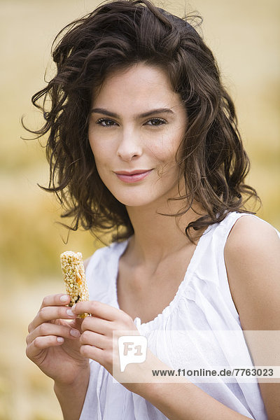 Portrait of young woman holding cereal bar