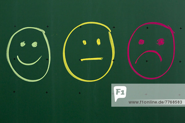 Drei Smileys  mit Kreide auf Schultafel gezeichnet