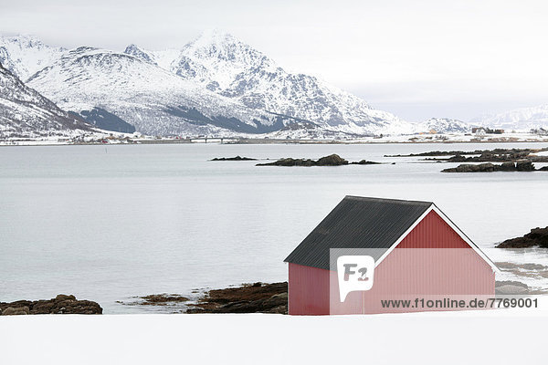 Wintery fjord landscape with a red boathouse