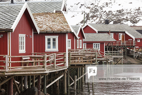 Fischerort mit roten Hütten am Fjord im Winter