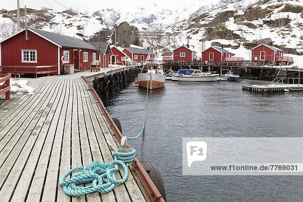 Kleiner Hafen mit roten Fischerhütten im Winter