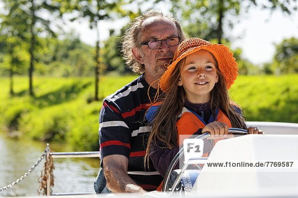 Vater und Tochter am Steuer einer Penichette  Hausboot  auf dem Canal de Pont-de-Vaux