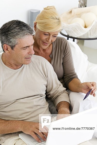 Mature couple using laptop  woman holding a credit card