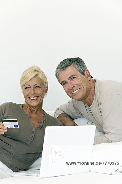 Mature couple using laptop  woman holding a credit card