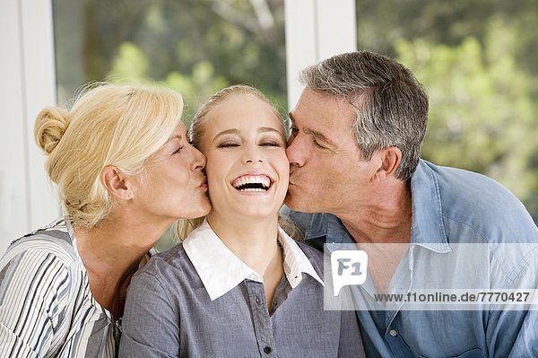 Mature couple kissing a young woman