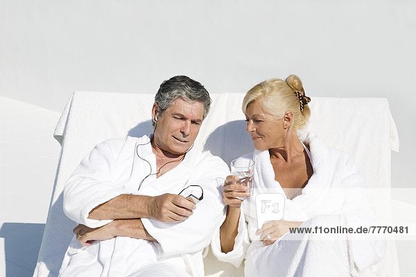 Mature couple wearing bathrobes  sitting on a terrace