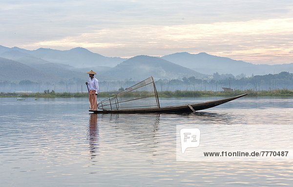 Intha leg rowing fishermen on Inle Lake who row traditional wooden boats using their leg and fish using nets stretched over conical bamboo frames  Inle Lake  Shan State  Myanmar (Burma)  Asia