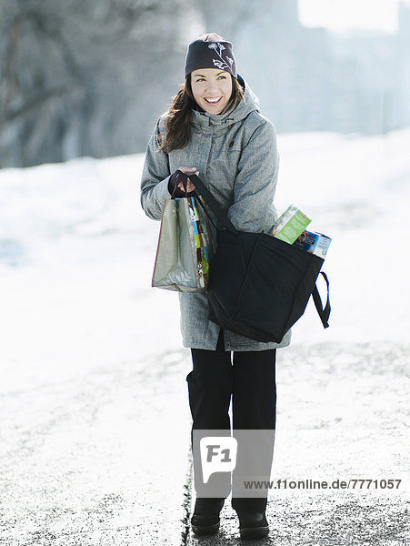 Junge Frau mit Einkaufstaschen im verschneiten Pfad